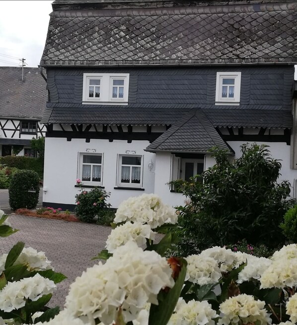 Un bâtiment traditionnel avec un toit recouvert de tuiles sombres, des murs blancs et de nombreuses fenêtres.