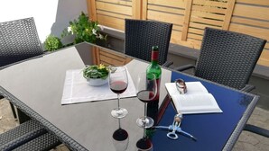 Une table avec une bouteille de vin rouge, des verres à vin, un menu et une petite plante.