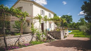 Une maison à deux étages avec un mur en pierre et un jardin.