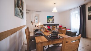 Un coin repas avec une table en bois dressée pour quatre personnes, un canapé et un tableau accroché au mur.
