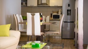 A modern kitchen with a dining area, featuring a sofa, chairs, and a glass table. - Villa Belmondo- Three Bedroom Villa with Terrace and Private Pool (Gruda)