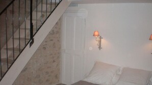 Un dormitorio con cama, escalera y puerta.