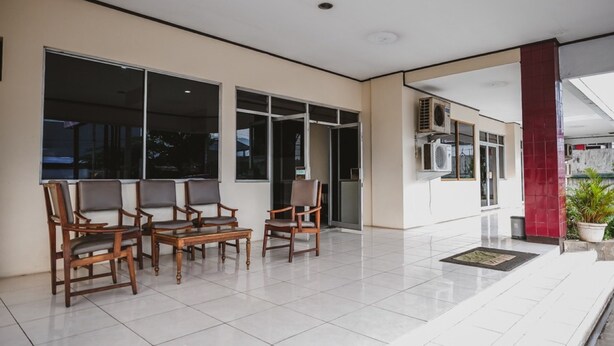 A spacious indoor area with a tiled floor, several wooden chairs, and a large window. - RedDoorz @ Ungaran (Ungaran)