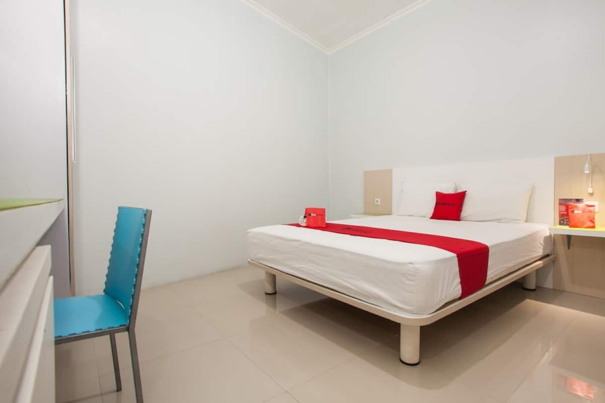 A hotel room with a bed, a chair, and a bedside table.