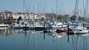 A marina with multiple boats docked, surrounded by buildings with red-tiled roofs. - Cozy studio near the beach with balcony (Les Sables-d'Olonne)