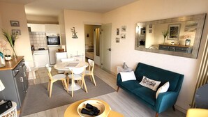 A compact living space with a dining area, a sofa, and a small table with binoculars. - Cozy studio near the beach with balcony (Les Sables-d'Olonne)