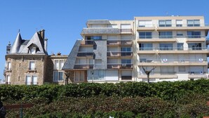 A modern building with a unique architectural design, featuring a mix of stone and glass materials. - Cozy studio near the beach with balcony (Les Sables-d'Olonne)