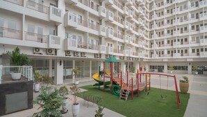 A multi-story residential building with balconies, a children's play area, and potted plants. - RedDoorz Apartment @ Sentul Tower (Citaringgul)