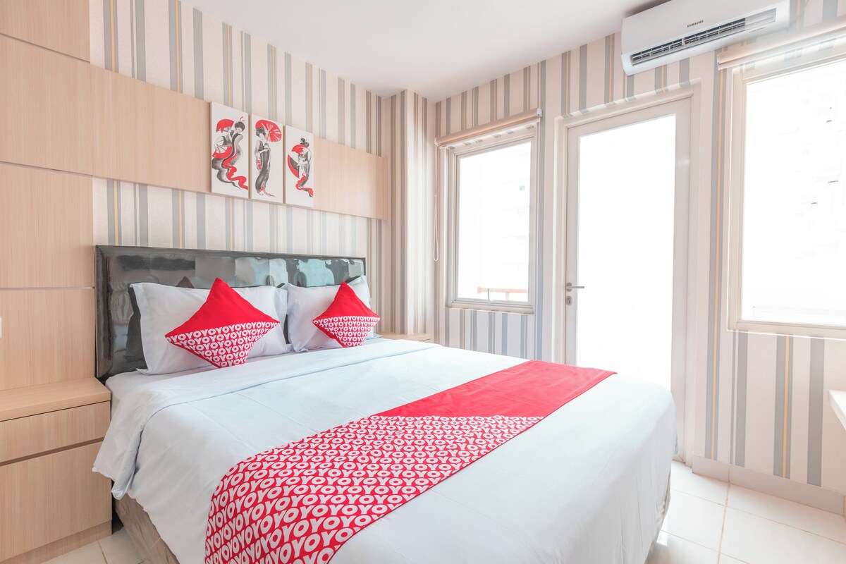 A hotel room with a bed, striped wallpaper, and a large window.