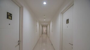 A long, narrow hallway with doors on both sides, each marked with a number. - RedDoorz Apartment @ Sentul Tower (Citaringgul)