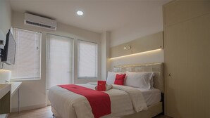 A bedroom with a bed, a bedside table, a TV, and an air conditioning unit. - RedDoorz Apartment @ Sentul Tower (Citaringgul)