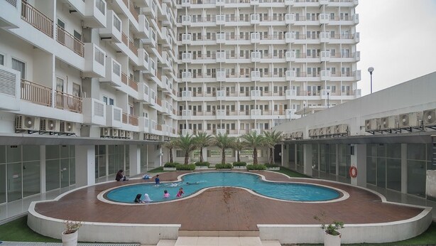 A modern apartment building with a central courtyard featuring a swimming pool. - RedDoorz Apartment @ Sentul Tower (Citaringgul)