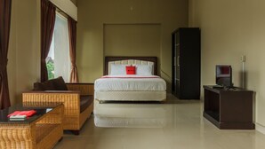 A hotel room with a bed, a sofa, a TV, and a desk. - RedDoorz Syariah near Taman Air Mancur Bogor (Bogor)