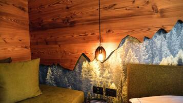 Una camera accogliente con pareti in legno, un letto con testiera verde e un murale raffigurante una montagna.