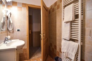 A bathroom with a sink, towel rack, and a shower area. - Hotel Cristallo (Andalo)