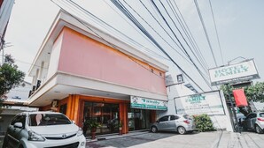 A hotel with a pink facade, a signboard for 'Hotel Family', and parked cars in front. - RedDoorz Plus @ Jalan Parangtritis 2 (Sewon)