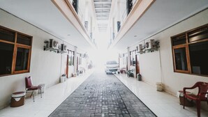 A corridor with a tiled floor, air conditioning units on the walls, and a vehicle in the distance. - RedDoorz Plus @ Jalan Parangtritis 2 (Sewon)