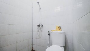 A small, tiled bathroom with a white toilet and a shower. - RedDoorz Plus @ Jalan Parangtritis 2 (Sewon)