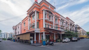 Un immeuble à plusieurs étages doté de balcons, avec une entrée au niveau du sol et des voitures garées.