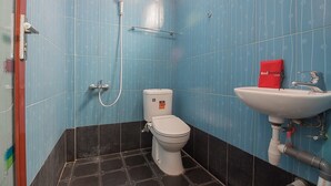 Une salle de bain avec des murs recouverts de carreaux bleus, des toilettes blanches, une serviette rouge et un lavabo blanc.