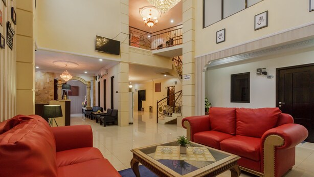 A spacious lobby with a red sofa, a glass coffee table, and a chandelier.