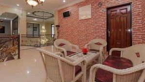 A lobby with wicker furniture, a chandelier, and a brick wall.