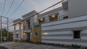 A modern hotel with a clean facade, a prominent sign, and a balcony with railings.
