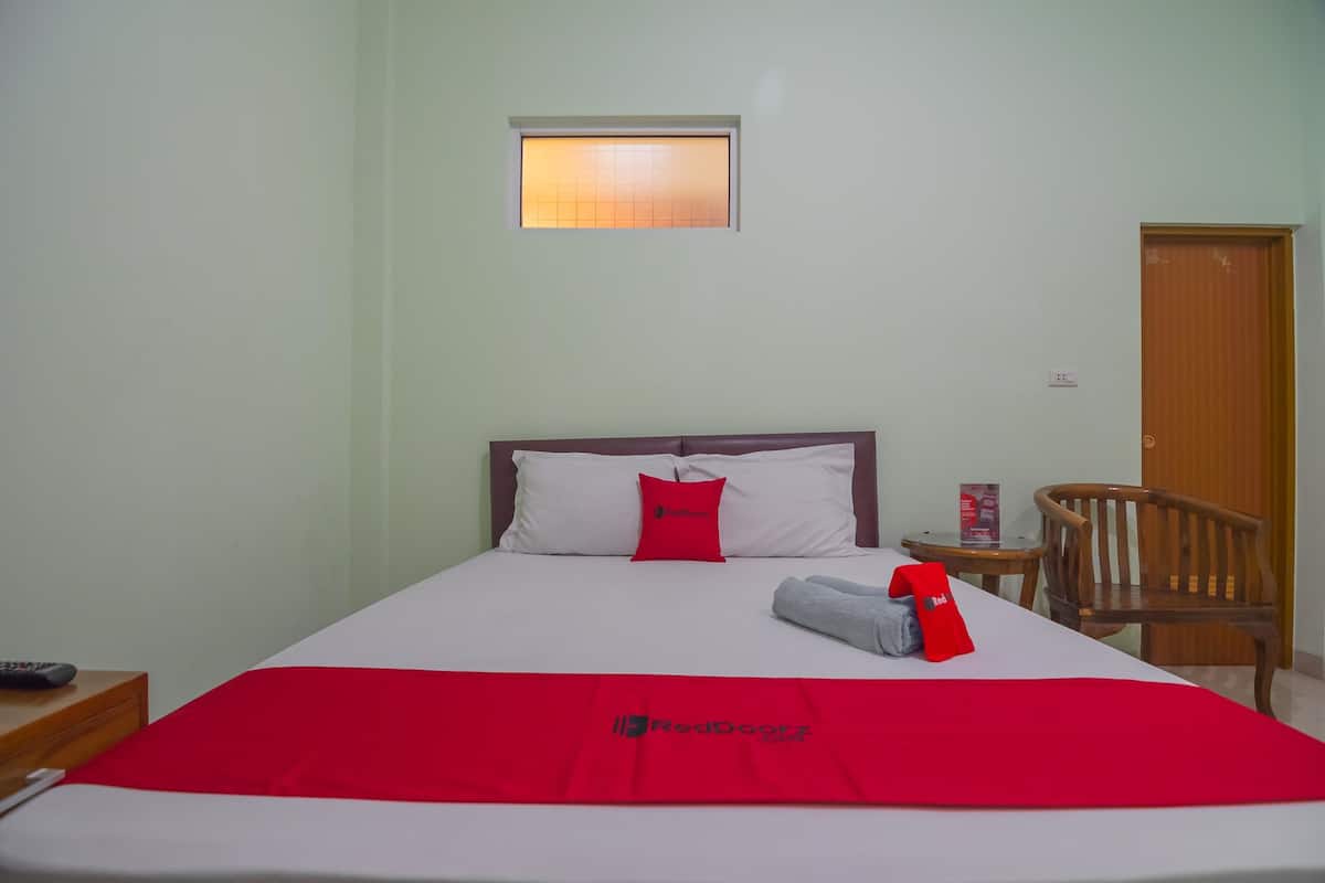 A hotel room with a bed, a small table, a chair, a window, and a door.