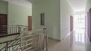 Ein geräumiger Flur mit einer Glas-Geländer-Treppe, hellgrünen Wänden und Blick auf einen Balkon.
