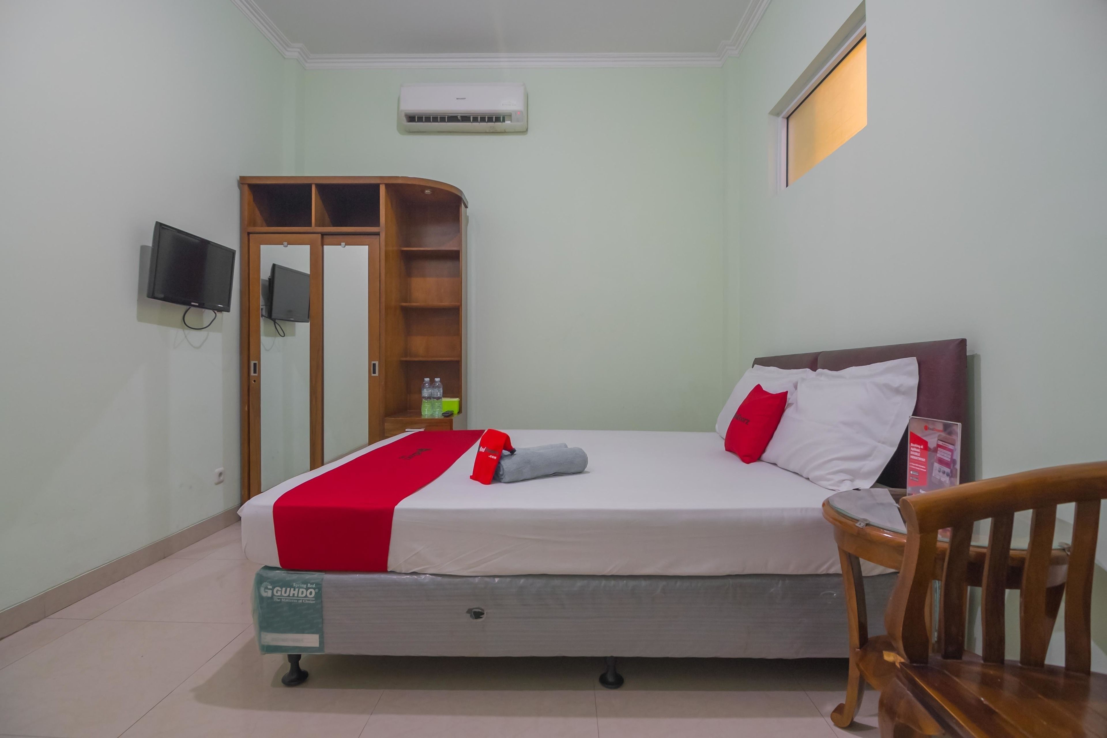A hotel room with a bed, a TV, a wardrobe, and a chair.