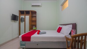 Ein Hotelzimmer mit Bett, Fernseher, Kleiderschrank und Stuhl.