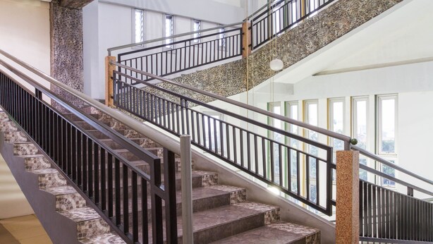A staircase with a stone and metal design, leading to an upper floor. - RedDoorz Plus @ Surapati 2 (Bandung)