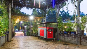 A covered walkway with a red vending machine, potted plants, and a brick wall. - RedDoorz Plus @ Surapati 2 (Bandung)