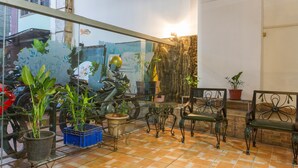 A patio area with potted plants, a glass table, metal chairs, and a motorcycle. - RedDoorz Plus @ Surapati 2 (Bandung)