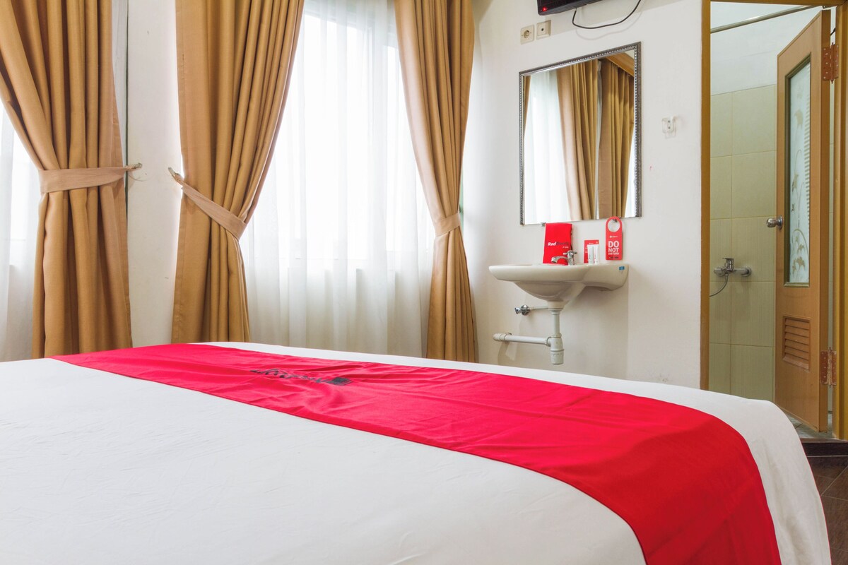 A hotel room with a bed, a sink, and a mirror.