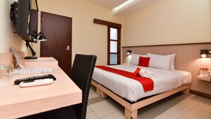 A hotel room with a bed, desk, chair, TV, and a window. - RedDoorz near Legian Street (Legian)