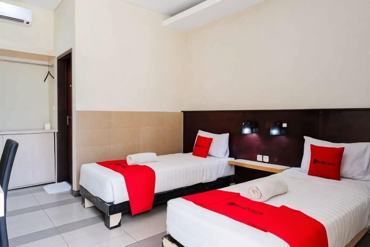 A hotel room with two beds, a desk, and a chair.