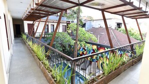 A covered balcony with a metal railing, potted plants, and a colorful mural on the wall. - RedDoorz near Legian Street (Legian)