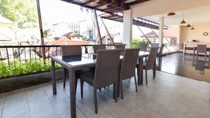 A dining area with wicker furniture, a view of buildings, and a balcony with a railing. - RedDoorz near Legian Street (Legian)