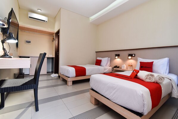 A hotel room with two beds, a desk, and a chair. - RedDoorz near Legian Street (Legian)