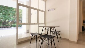 A room with a large window, a table with four chairs, and a sign on the wall. - RedDoorz near Jogja City Mall 3 (Pogung Lor)