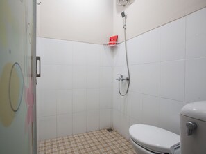 Un baño pequeño y limpio con azulejos blancos, inodoro y ducha con cabezal de ducha manual.