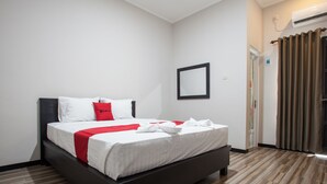 A modern hotel room with a bed, a mirror, and an air conditioning unit. - RedDoorz Plus near Banyuwangi Airport (Rogojampi)