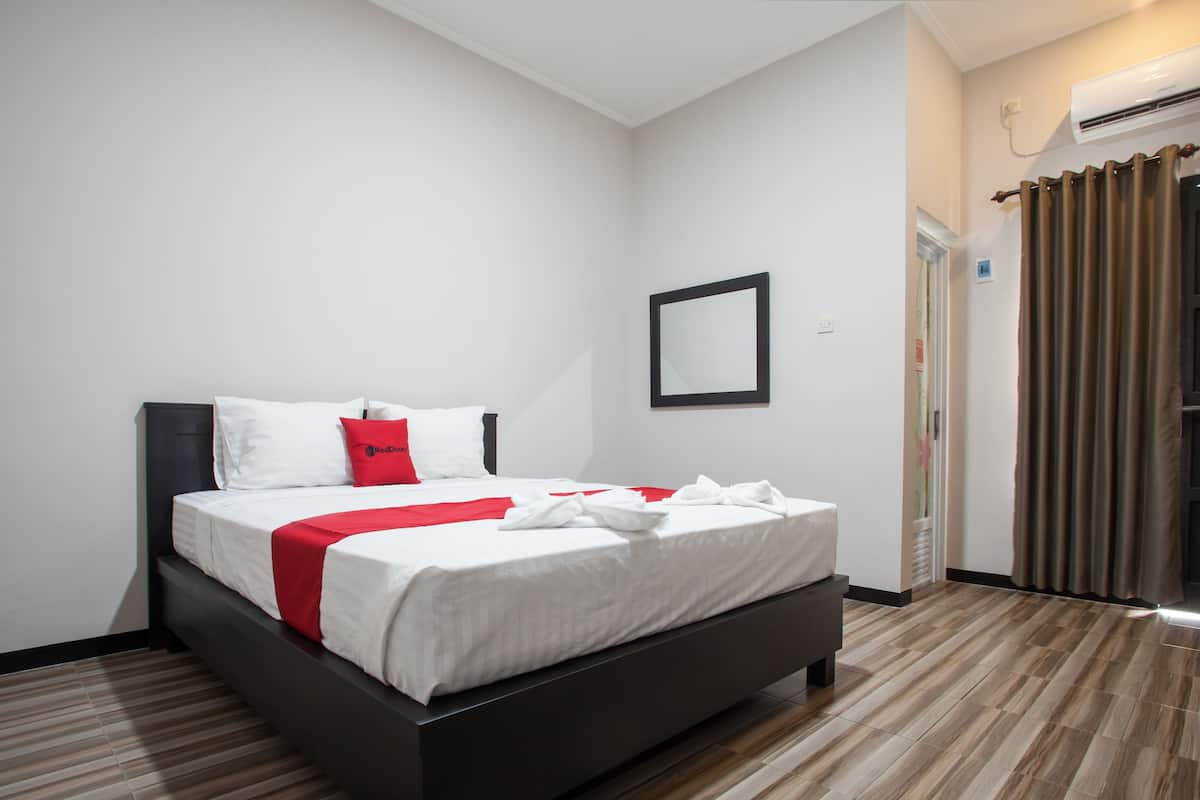 Una habitación de hotel moderna con cama, espejo y aire acondicionado.