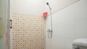 A bathroom with a shower, toilet, and patterned tiles. - RedDoorz Plus near Banyuwangi Airport (Rogojampi)