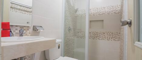 A bathroom with a white sink, toilet, and glass-enclosed shower.