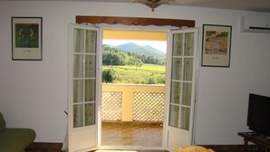 An open door leading to a balcony with a view of a green landscape.