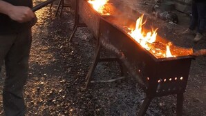 A person cooking on an open fire outdoors.