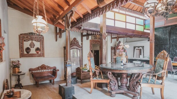 A traditional wooden interior with a round dining table, ornate chairs, and decorative elements like mirrors and wall art. - RedDoorz near Galeria Mall 2 (Yogyakarta)