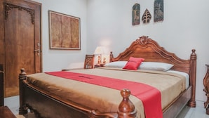 A wooden bed with a red blanket, a wooden door, and a wall with framed artwork. - RedDoorz near Galeria Mall 2 (Yogyakarta)